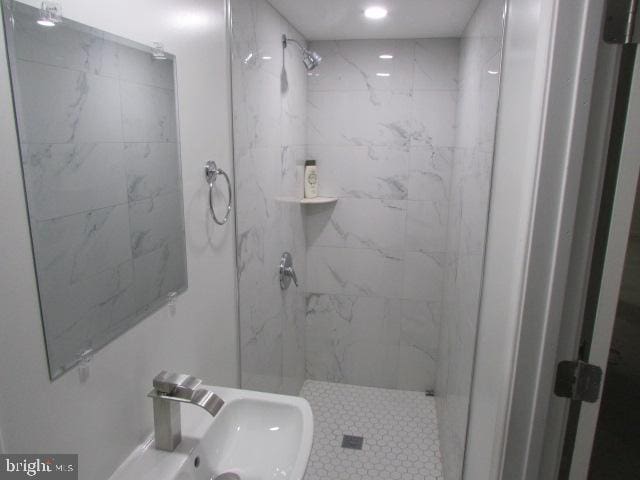 bathroom with tiled shower and sink