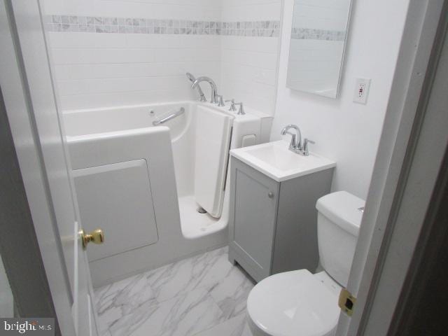 bathroom featuring vanity, toilet, and a tub to relax in