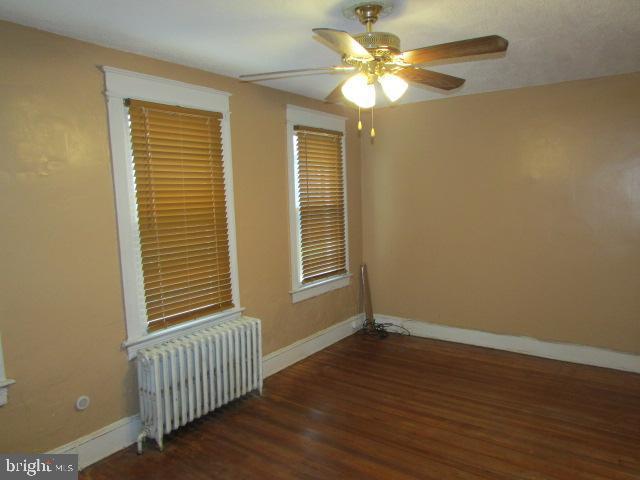 spare room featuring radiator, ceiling fan, and dark hardwood / wood-style floors