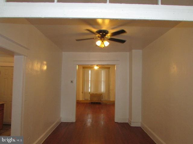 corridor with dark hardwood / wood-style flooring and radiator