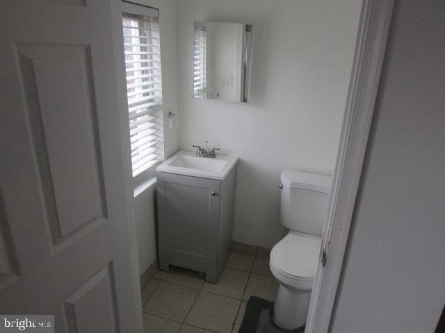 bathroom featuring tile patterned floors, a wealth of natural light, vanity, and toilet