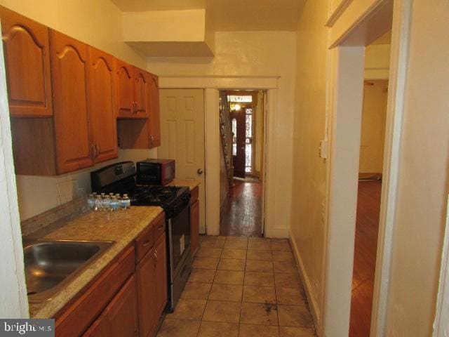 kitchen featuring dark tile patterned floors, black appliances, and sink