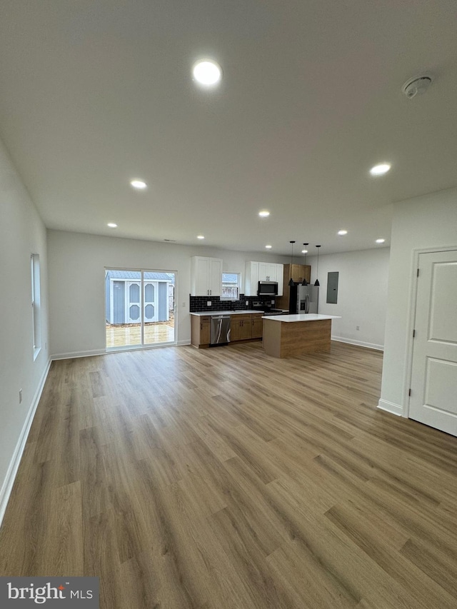 unfurnished living room with electric panel and light hardwood / wood-style flooring