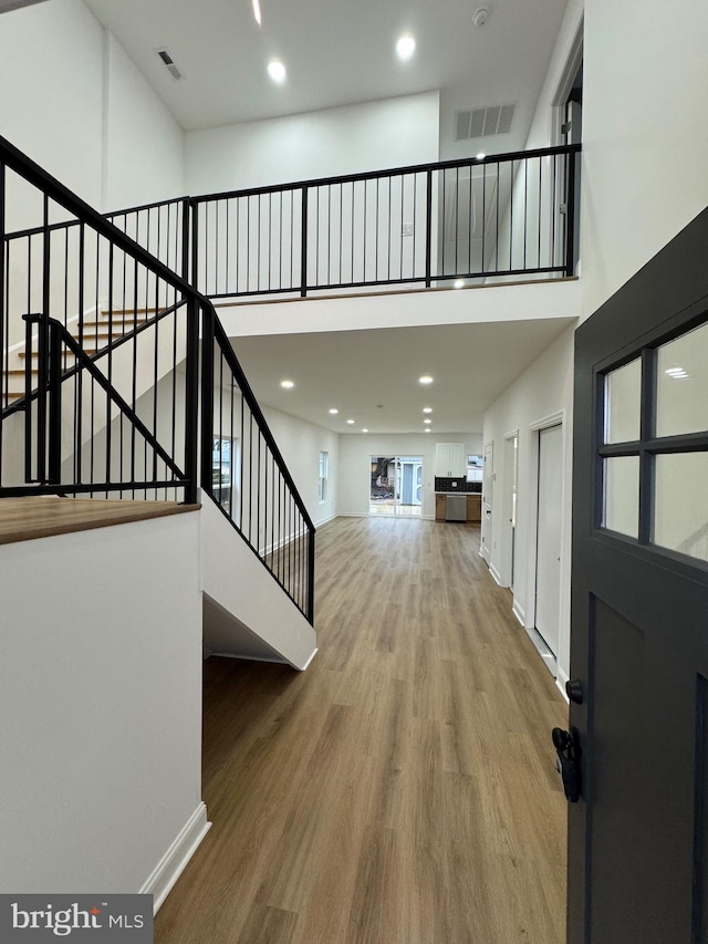 foyer entrance with wood-type flooring and a towering ceiling