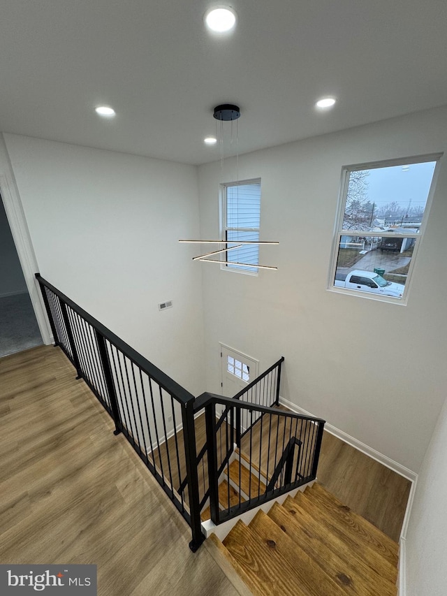 stairway featuring hardwood / wood-style floors and a notable chandelier