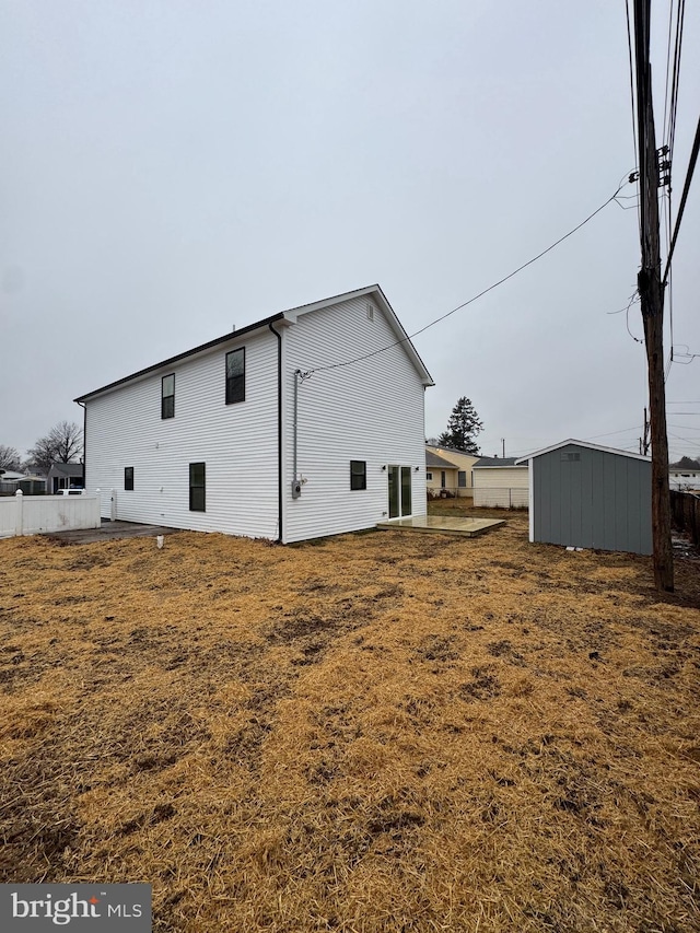 back of house with a storage shed