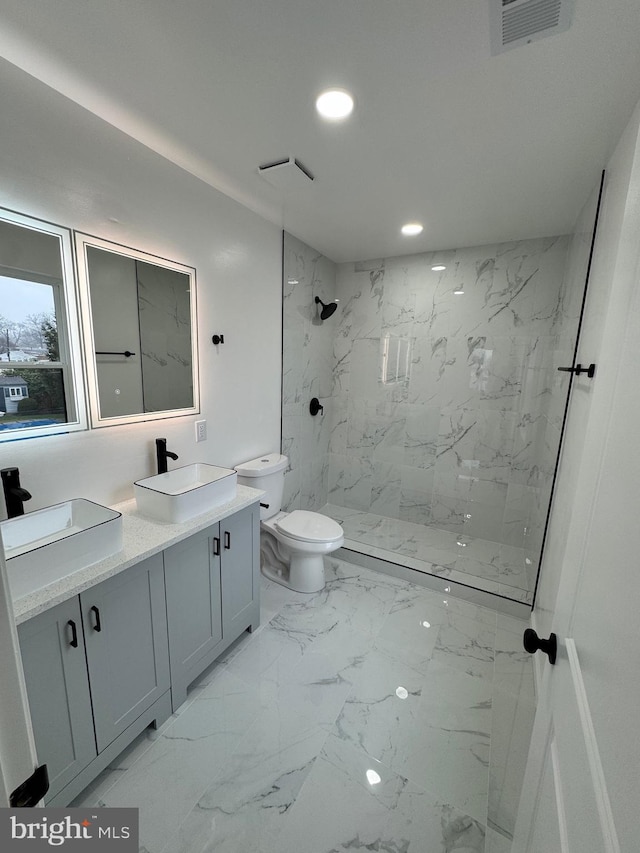 bathroom featuring toilet, vanity, and tiled shower