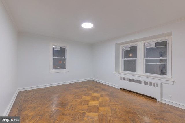 empty room with dark parquet flooring and radiator