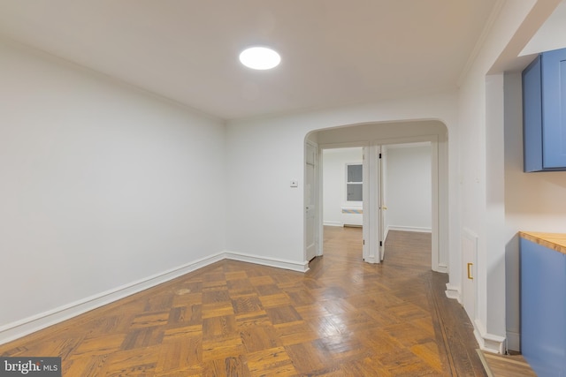 unfurnished room featuring dark parquet flooring and ornamental molding