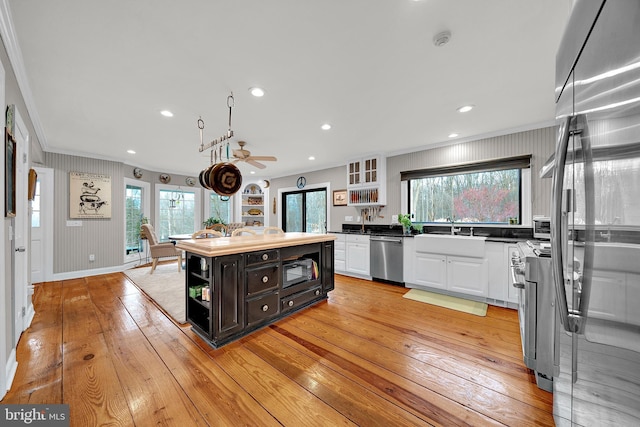 kitchen with white cabinetry, a center island, sink, crown molding, and appliances with stainless steel finishes