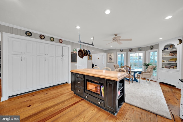 kitchen with light hardwood / wood-style floors, a kitchen island, ceiling fan, and ornamental molding