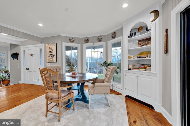 dining area featuring built in features, crown molding, and light hardwood / wood-style flooring