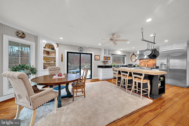 dining area featuring built in shelves, ceiling fan, and light hardwood / wood-style flooring