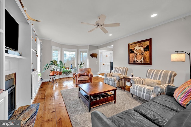 living room featuring crown molding, built in features, ceiling fan, and light hardwood / wood-style floors