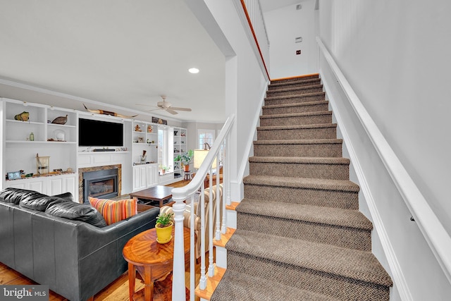 stairs with hardwood / wood-style floors, ceiling fan, and ornamental molding