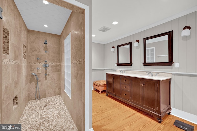 bathroom with crown molding, hardwood / wood-style floors, vanity, and tiled shower