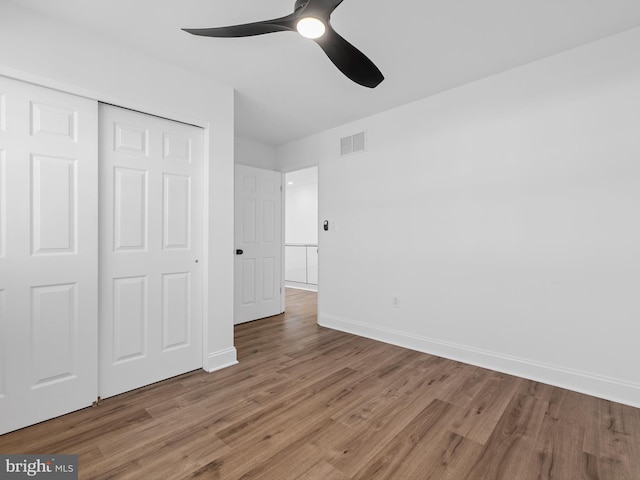 unfurnished bedroom with hardwood / wood-style floors, a closet, and ceiling fan