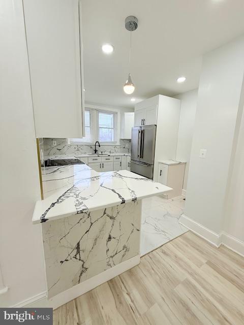 kitchen with light stone countertops, white cabinetry, hanging light fixtures, stainless steel appliances, and kitchen peninsula