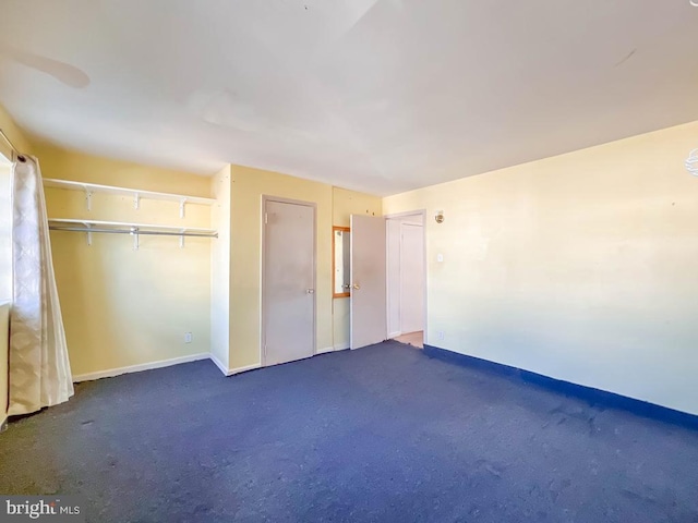 unfurnished bedroom with dark colored carpet and a closet