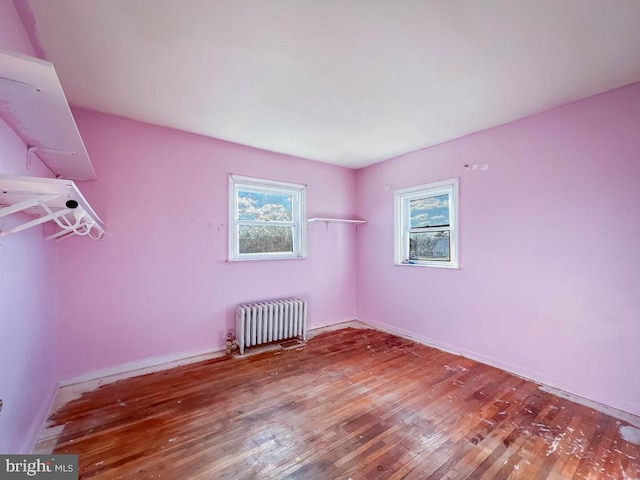 unfurnished room featuring hardwood / wood-style flooring and radiator heating unit