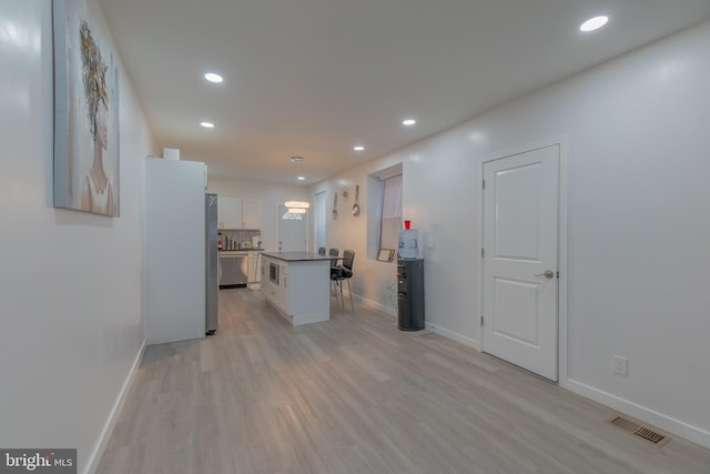 kitchen with dishwasher, a center island, white cabinets, light wood-type flooring, and decorative light fixtures