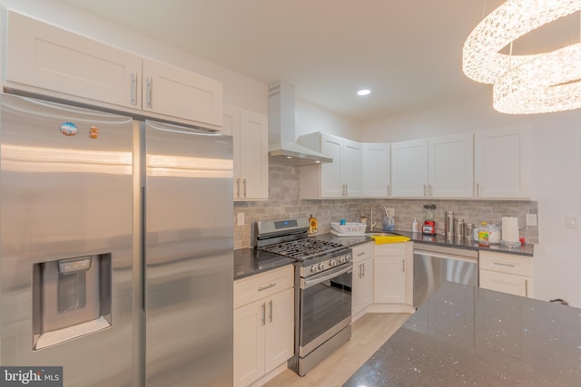 kitchen with backsplash, white cabinets, stainless steel appliances, and wall chimney range hood