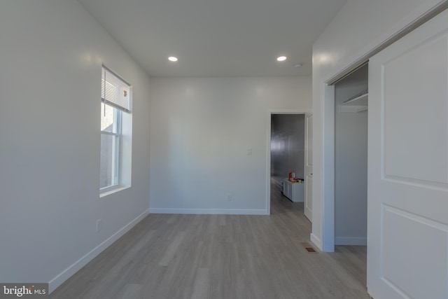 unfurnished bedroom with light wood-type flooring and a closet