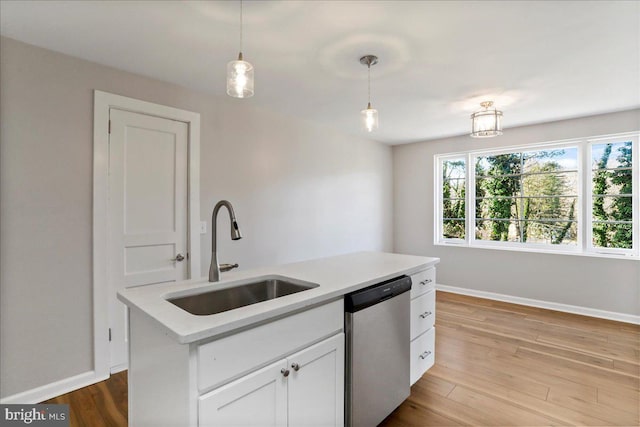 kitchen featuring dishwasher, white cabinets, a center island with sink, sink, and decorative light fixtures