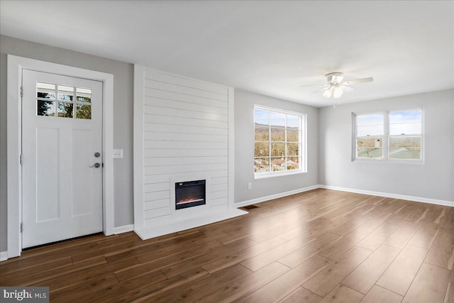 unfurnished living room featuring a fireplace, dark hardwood / wood-style flooring, and ceiling fan