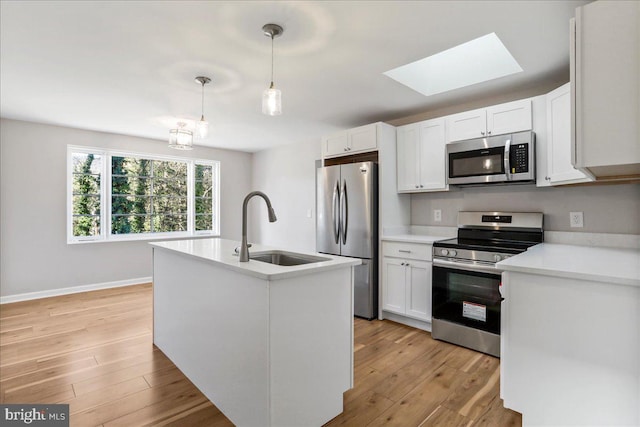 kitchen with a skylight, sink, stainless steel appliances, decorative light fixtures, and white cabinets