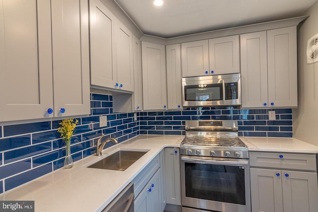 kitchen featuring light stone countertops, stainless steel appliances, tasteful backsplash, and sink