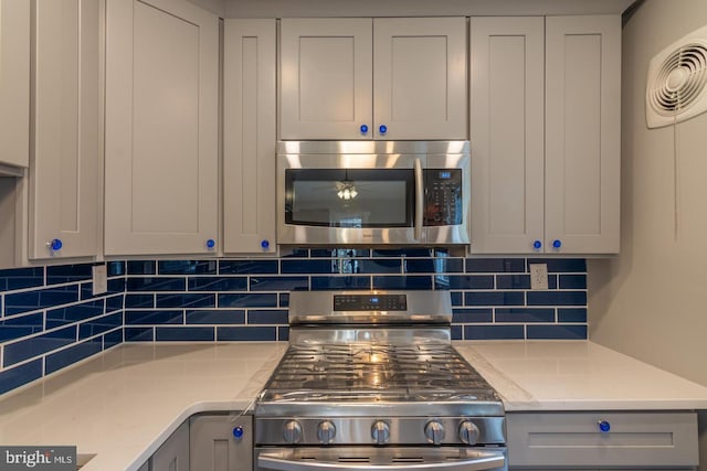 kitchen with decorative backsplash, light stone counters, and appliances with stainless steel finishes