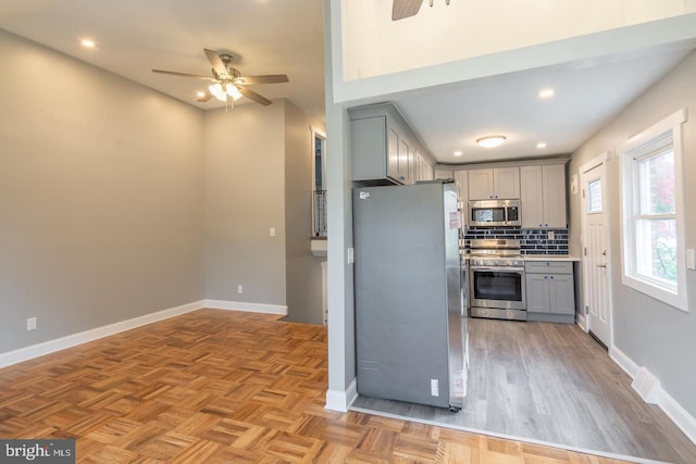 kitchen with ceiling fan, decorative backsplash, gray cabinets, and appliances with stainless steel finishes