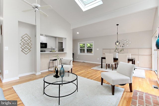 5284 Davis Ford Rd, Woodbridge, VA 22192 - living room with light wood-style floors, baseboards, ceiling fan, high vaulted ceiling, and a skylight
