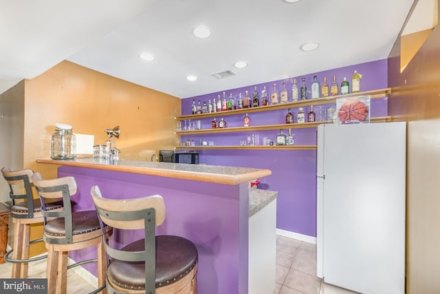 bar with light tile patterned flooring and white fridge