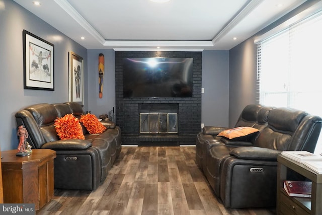 living room featuring a fireplace, a tray ceiling, and hardwood / wood-style floors