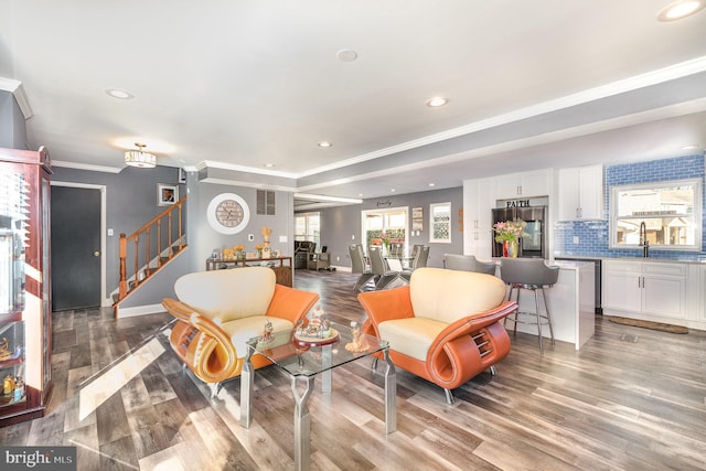 living room featuring ornamental molding, wood-type flooring, and sink