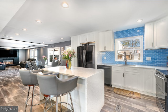 kitchen featuring stainless steel appliances, white cabinetry, a breakfast bar, and backsplash