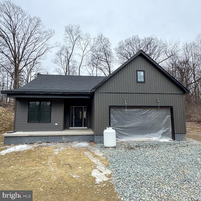 view of front of home with a garage, driveway, a porch, and roof with shingles