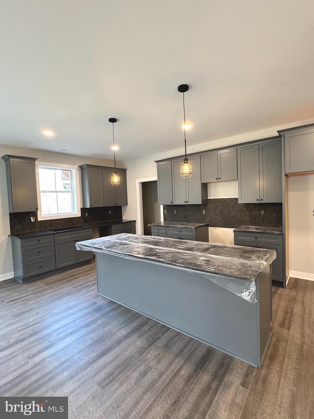 kitchen with tasteful backsplash, dark wood-type flooring, a center island, and gray cabinetry