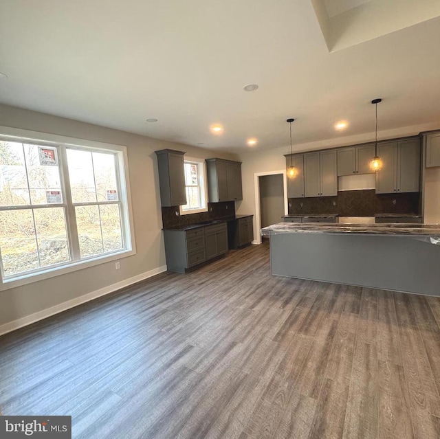 kitchen featuring baseboards, dark wood-style floors, decorative light fixtures, gray cabinetry, and backsplash