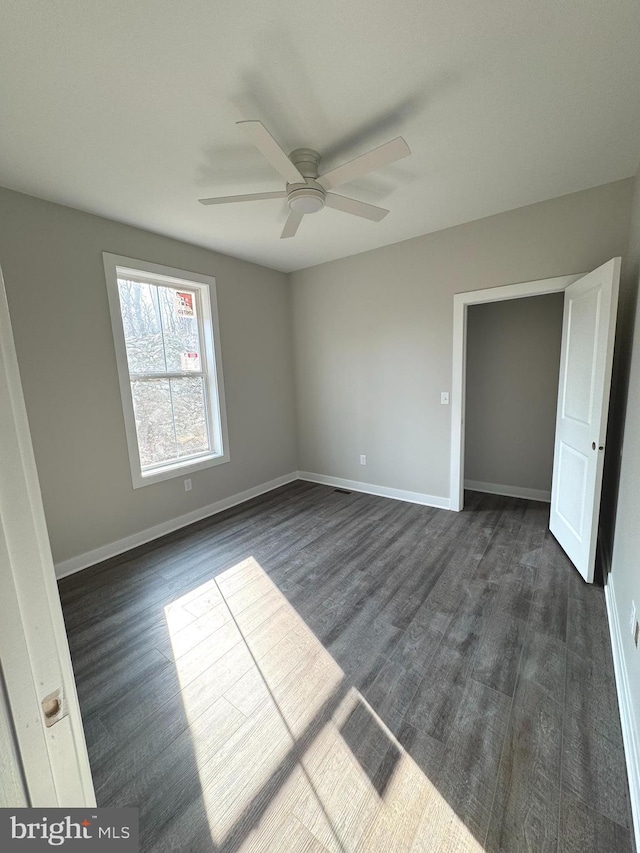 unfurnished bedroom featuring dark wood-style floors, ceiling fan, visible vents, and baseboards