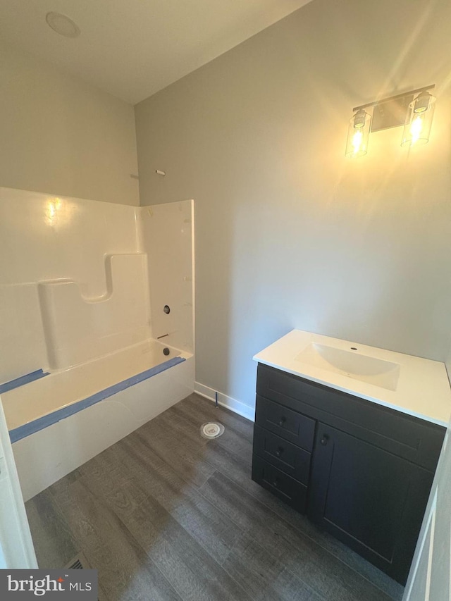 bathroom with washtub / shower combination, baseboards, wood finished floors, and vanity