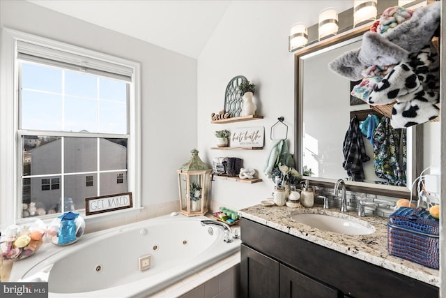 bathroom featuring vaulted ceiling, tiled bath, and vanity