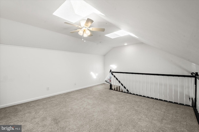 additional living space with ceiling fan, carpet flooring, and vaulted ceiling with skylight