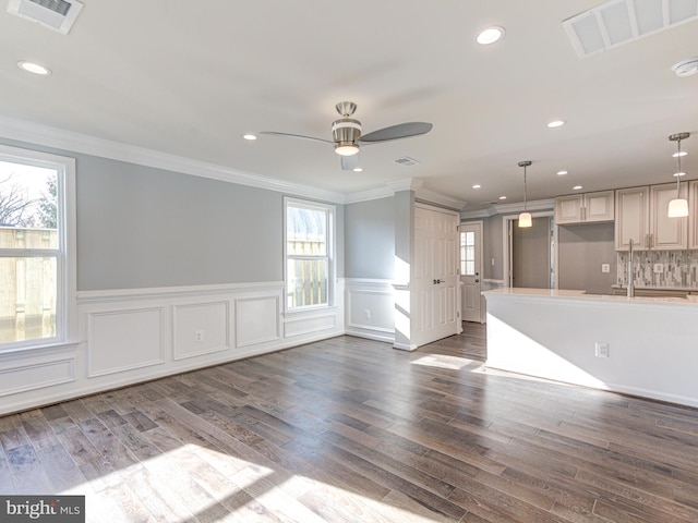 unfurnished living room featuring dark hardwood / wood-style floors, ceiling fan, and ornamental molding