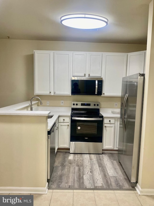 kitchen featuring white cabinets, light tile patterned flooring, kitchen peninsula, and stainless steel appliances