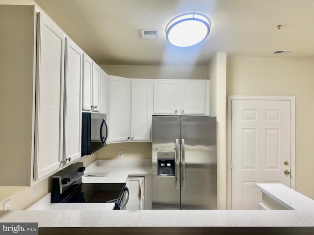 kitchen featuring black electric range, stainless steel fridge, white cabinetry, and light stone counters