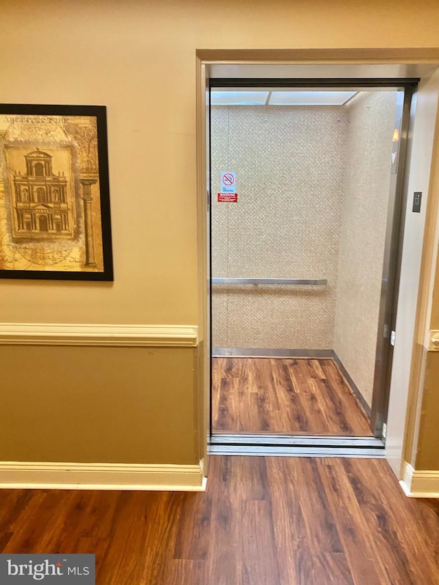 details featuring elevator and hardwood / wood-style flooring