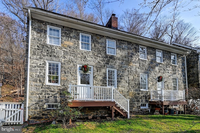 rear view of house with a wooden deck and a yard